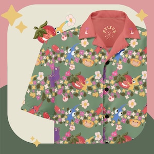 May include: Green button-up shirt with a colorful pattern of strawberries, flowers, and cartoon characters. The shirt has a coral-colored collar and the text "PYIXUS" on the inside of the collar.