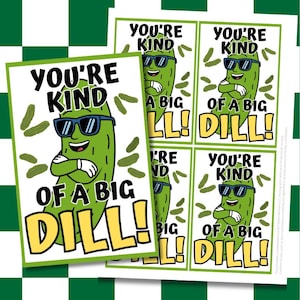 May include: A stack of printed cards with a green pickle cartoon wearing sunglasses and the text "YOU'RE KIND OF A BIG DILL!" on a white background. The cards are on a green and white checkered background.