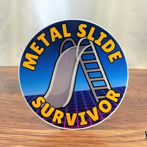 Puede incluir: Una pegatina redonda con un dise&ntilde;o retro que presenta un tobog&aacute;n y una escalera. El texto "METAL SLIDE SURVIVOR" es de color amarillo, con un fondo azul y morado. La pegatina tiene un borde blanco.