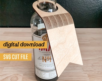 May include: A wooden bottle holder with a flag-shaped design. The holder is made of light brown wood and has a cut-out for a bottle neck. The holder is designed to hold a bottle of liquor.
