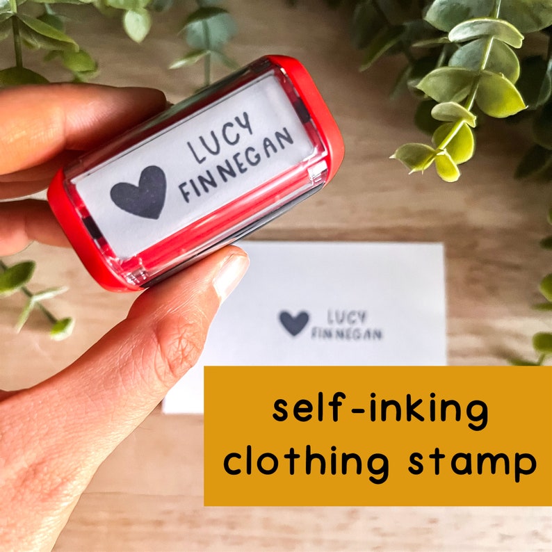 May include: Red self-inking clothing stamp with a white label that says "LUCY FINNEGAN" and a black heart.