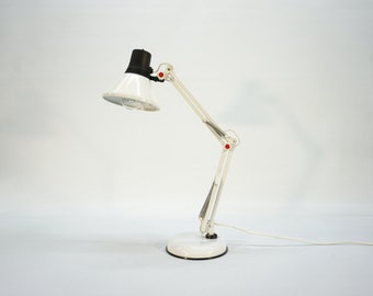 May include: White desk lamp with a black shade and a flexible arm. The lamp has a white base and a white cord.