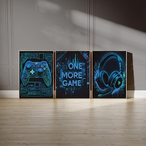 May include: Three framed art prints with a gaming theme. The prints feature a neon blue and green game controller, the text "ONE MORE GAME", and a headset. The art is set against a dark background.