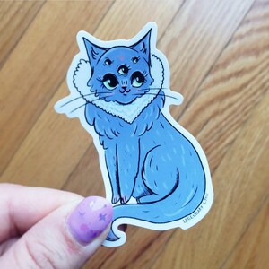 May include: A blue cat sticker with three eyes and a fluffy white collar. The cat is sitting with its tail curled around its body. The sticker has the text "Legendary Life" at the bottom.
