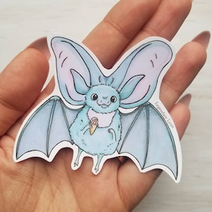 May include: A blue and purple bat with large ears holds a pink and brown ice cream cone. The bat is drawn in a cartoon style with a fluffy appearance. The background is white.