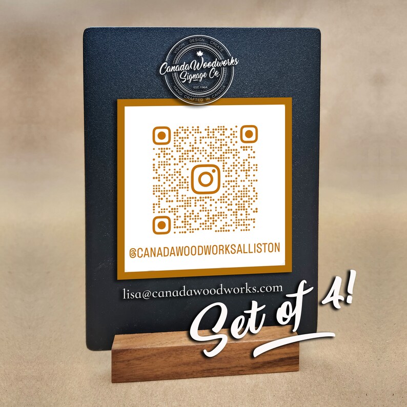 Puede incluir: Un letrero negro de pizarra con un c&oacute;digo QR dorado y el texto "@CANADAWOODWORKSALLISTON" y "lisa@canadawoodworks.com". El letrero est&aacute; sobre un soporte de madera y tiene el texto "Set of 4!" escrito en cursiva blanca.