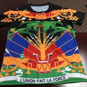 May include: A black short-sleeved t-shirt with a colorful design featuring a flag with cannons, palm trees, and the text "L'UNION FAIT LA FORCE".