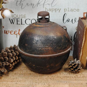 May include: An antique, spherical Toledo Torch oil lamp with a rusted, aged appearance. The lamp has a handle and text that reads "THE TOLEDO TORCH PRESSED STEEL CO. TOLEDO, OHIO, U.S.A. PAT. 1732708".