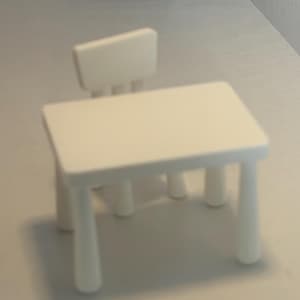 May include: A small, white wooden table and chair set. The table has a rectangular top and four rounded legs. The chair has a small backrest. The set is designed for children's play or dollhouse use.