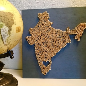 May include: A blue wooden board with a gold string art design of India. The string art design includes a small heart in the center of India.