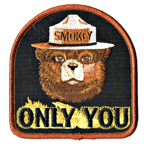 May include: A brown bear wearing a ranger hat with the word "Smokey" on it. The bear is looking directly at the viewer. The text "Only You" is written below the bear in yellow letters with a black outline.