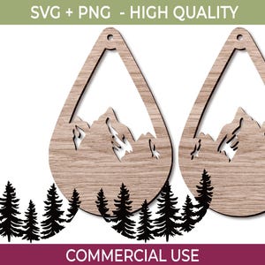 May include: Two wooden teardrop-shaped earrings with mountain and tree cutouts. The earrings have a light brown wood grain finish. Below the earrings is a black silhouette of pine trees. The text "SVG + PNG - HIGH QUALITY" is at the top, and "COMMERCIAL USE" is at the bottom.