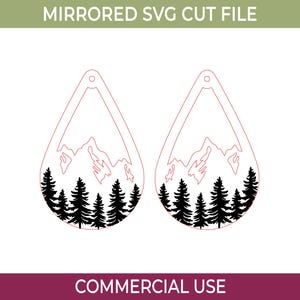 May include: Mirrored SVG cut file featuring two teardrop-shaped designs. Each design has a mountain range silhouette above a row of black pine trees. The text "COMMERCIAL USE" is at the bottom.