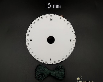 May include: A white plastic bead sizing tool with a black centre hole and numbers from 1 to 32 around the edge. The tool is 15 mm in diameter. A spool of dark green string is also shown.