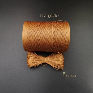 May include: A spool of brown waxed cord with the text "113 giallo" printed on a black background.