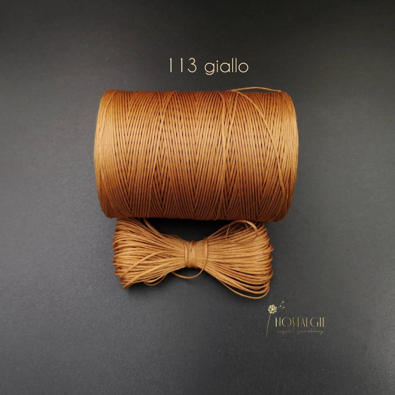 May include: A spool of brown waxed cord with the text "113 giallo" printed on a black background.