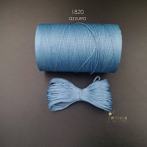 May include: A spool of light blue waxed cord, labelled "1820 azzurro", with a small bow of the same cord in front of it.