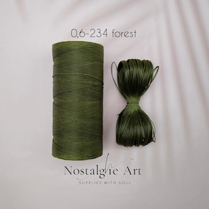 Puede incluir: Dos carretes de hilo de lino encerado verde bosque. Uno es cilíndrico y vertical, el otro es un paquete más pequeño. El texto "0,6-234 forest" está encima de los carretes. El texto "Nostalgie Art SUPPLIES WITH SOUL" está debajo.