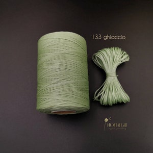 Puede incluir: Una bobina de cordón encerado verde con un trozo más pequeño del mismo cordón al lado. El texto "133 ghiaccio" está escrito encima de los cordones.