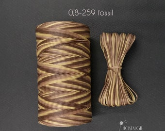 May include: A spool of brown, beige, and yellow waxed cord with a label that reads "0,8-259 fossil".