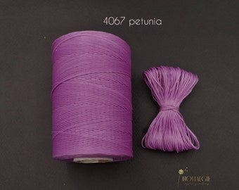 May include: A spool of purple waxed cotton cord, labeled "4067 petunia", with a small sample of the cord tied in a bow.