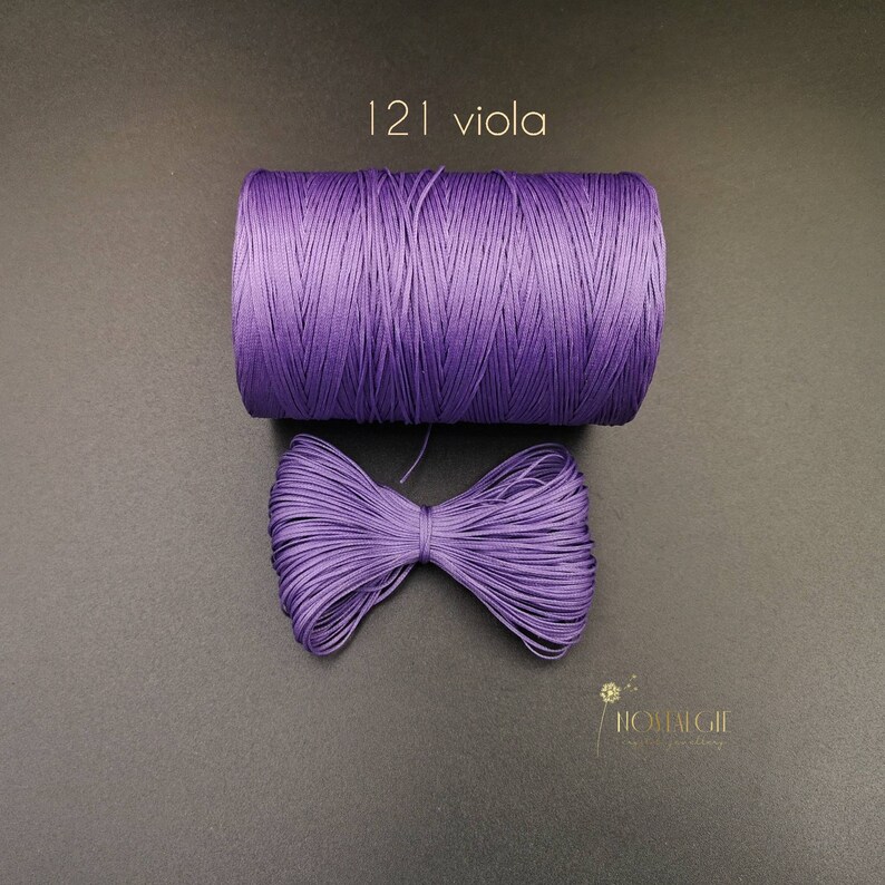 May include: A spool of purple cord with a bow made from the same cord. The text "121 viola" is printed above the spool.