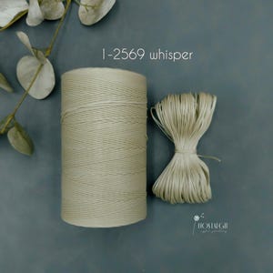 May include: A spool of whisper-colored twine and a bundle of the same twine. The twine is a light, neutral color. The text "1-2569 whisper" is in the upper right corner. The background is a muted teal color.