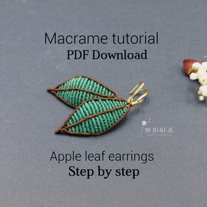 Peut inclure: Une paire de boucles d'oreilles en macramé en forme de feuille de pomme de couleur vert sarcelle avec des accents marrons et des crochets dorés. Les boucles d'oreilles sont sur un fond gris avec le texte "Tutoriel de macramé Téléchargement PDF" et "Boucles d'oreilles en forme de feuille de pomme Étape par étape".