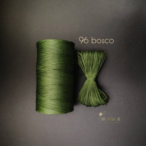 Puede incluir: Un carrete de cordón verde oscuro, etiquetado como "96 bosco", se muestra junto a un trozo más pequeño del mismo cordón. El cordón es un tipo de cordón encerado que se utiliza para la elaboración de joyas.