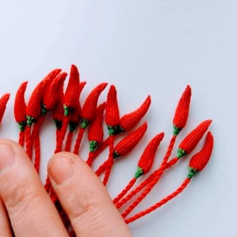 Peut inclure: Un bouquet de piments rouges en crochet avec des tiges vertes. Les piments sont dispos&eacute;s en &eacute;ventail et sont tenus dans une main.