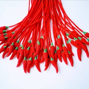 Peut inclure: Un groupe de glands en forme de piment rouge et vert suspendus &agrave; une ficelle.