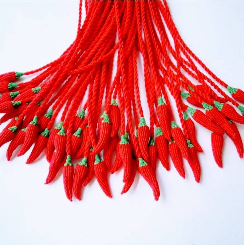 Peut inclure: Un groupe de glands en forme de piment rouge et vert suspendus &agrave; une ficelle.