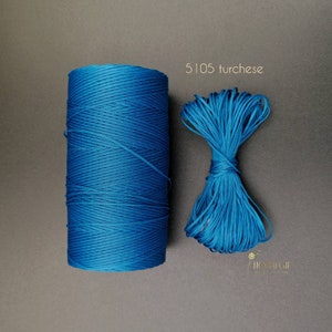 Puede incluir: Una bobina de cordón de algodón encerado azul turquesa, con una pequeña cantidad de cordón enrollado en un paquete suelto al lado. El texto "5105 turchese" está impreso sobre el paquete.