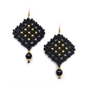 K&ouml;nnte beinhalten: Ein Paar schwarze Makramee-Ohrringe mit goldfarbenen Akzenten. Jeder Ohrring hat ein rautenf&ouml;rmiges Design mit goldenen Perlen und einer schwarzen Perle am unteren Ende. Die Ohrringe haben goldfarbene Ohrhaken.