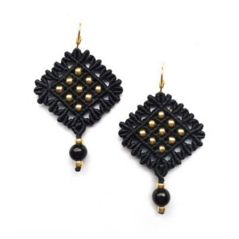 K&ouml;nnte beinhalten: Ein Paar schwarze Makramee-Ohrringe mit goldfarbenen Akzenten. Jeder Ohrring hat ein rautenf&ouml;rmiges Design mit goldenen Perlen und einer schwarzen Perle am unteren Ende. Die Ohrringe haben goldfarbene Ohrhaken.