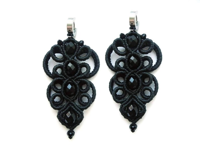 May include: A pair of black dangle earrings with intricate knotted designs and black crystal beads.