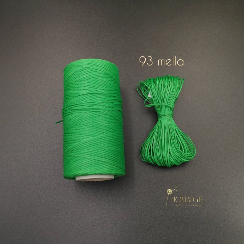 May include: A spool of bright green waxed cord, with a smaller length of the same cord laid out next to it. The text "93 mella" is printed on a white background.
