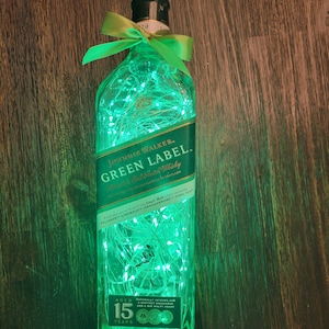 May include: A clear glass bottle with green lights inside. The bottle is labeled "Johnnie Walker Green Label" and "Blended Scotch Whisky". The label also includes the text "Aged 15 Years".