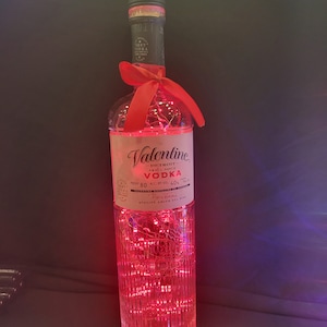 May include: A clear glass bottle of Valentine Detroit Vodka with a red ribbon and fairy lights wrapped around it. The bottle is 80 proof and 40% alcohol by volume. The label reads "Detroit Small Batch Vodka".