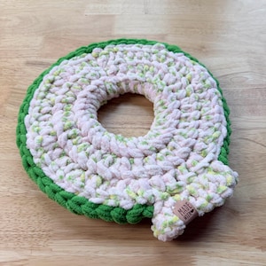 Peut inclure: Un dessous de verre fait à la main, crocheté en forme de tranche de pastèque. Le dessous de verre présente un centre rose avec des accents verts et jaunes, et une bordure verte. Une petite étiquette avec "MADE WITH LOVE" est attachée.
