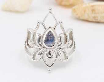 May include: A silver ring with a delicate lotus flower design and a blue moonstone in the center.