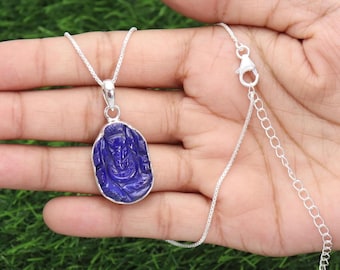 May include: A silver necklace featuring a carved, oval-shaped, deep blue pendant. The pendant depicts a detailed figure. The necklace has a delicate silver chain with an adjustable length.
