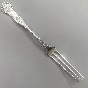 May include: A silver-toned metal fork featuring a decorative handle with a beaded edge and a shell-like motif at the top. The slender stem also displays a beaded texture that extends down to the base of the three long, pointed tines.