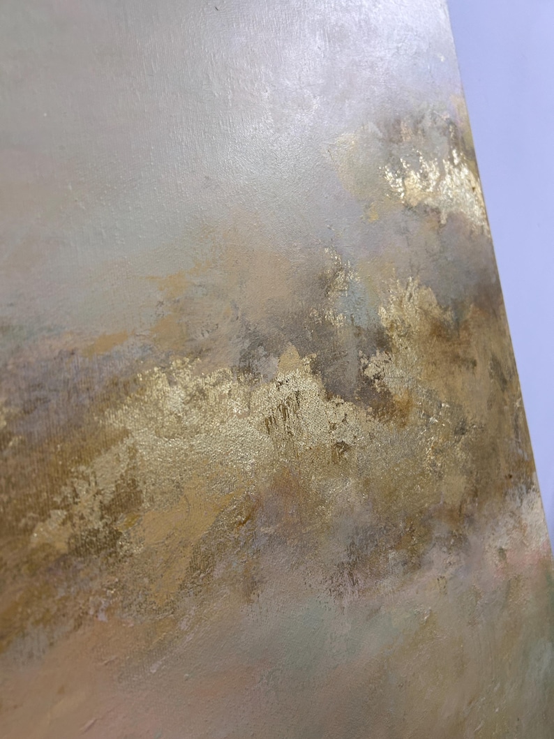 Op de afbeelding: Abstract schilderij met een textuur, gelaagde look. De achtergrond is lichtgrijs met hints van roze en groen. De voorgrond is goudkleurig met een metallic glans.