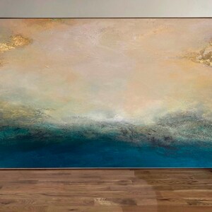 Op de afbeelding: Abstract schilderij met een lichtbeige achtergrond en een donkerblauwe onderkant. Het schilderij heeft een textuur en gouden accenten.