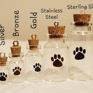 May include: Five small glass bottles with cork stoppers and silver, bronze, gold, stainless steel, and sterling silver caps. Each bottle has a black paw print sticker on the front.