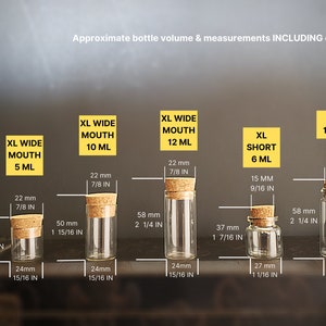 May include: Five glass bottles with cork stoppers in various sizes. The bottles are labeled with their approximate volume in milliliters and inches. The bottles are clear glass and have a round shape.