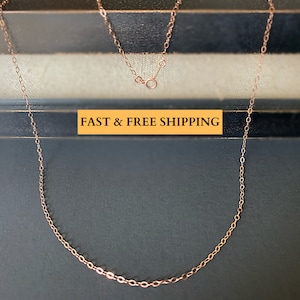 May include: A rose gold chain necklace with a lobster clasp closure. The chain is made of small, oval-shaped links.  "FAST & FREE SHIPPING" is written in yellow text on a black background.