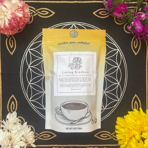 May include: A yellow pouch with the text "awaken your potential" and "Loving Kindness" printed on it. The pouch contains a blend of raw ceremonial cacao, herbs, and spices. The text on the pouch also includes the ingredients and net weight of 5.5 oz (156g).