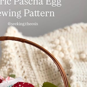 Puede incluir: Una cesta de mimbre llena de huevos de Pascua de tela roja, un paquete amarillo con el texto "YUMEARTH" y un pequeño icono dorado. La cesta está sobre una superficie blanca con una planta verde.